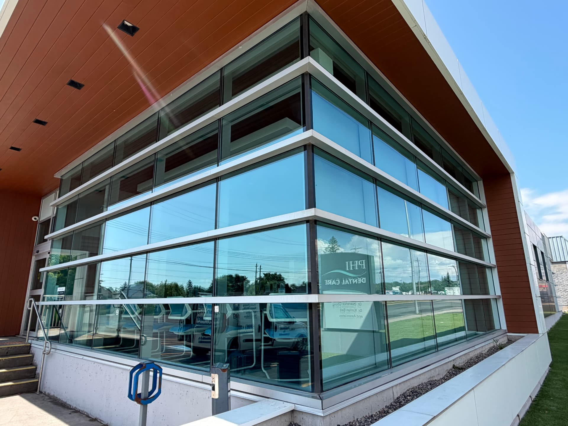 Streak-free commercial glass facade cleaned by Imperial Cleaning in Sault Ste. Marie, with the service van reflected in the windows