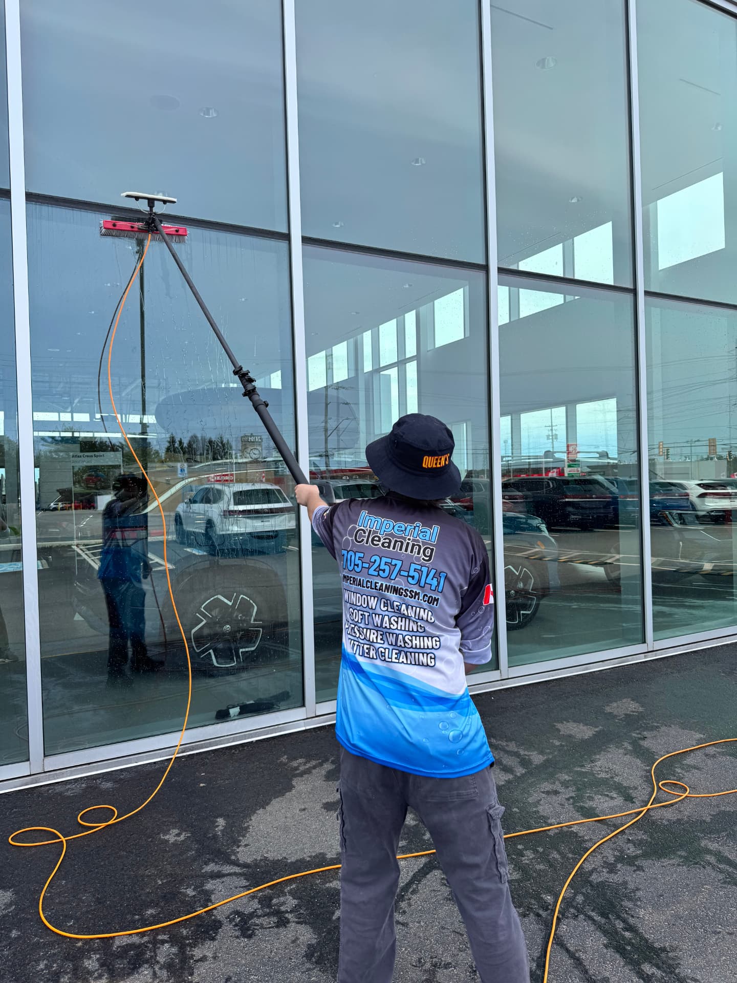 Imperial Cleaning technician using a water-fed pole to clean commercial storefront glass in Sault Ste. Marie